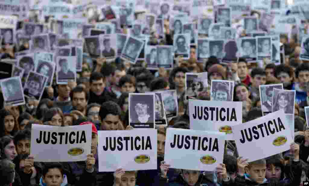 Người biểu tình cầm biểu ngữ với chữ "Công lý" trong tiếng Tây Ban Nha và hình ảnh của những nạn nhân vụ đánh bom năm 1994 nhằm vào trung tâm cộng đồng Do Thái AMIA trong một buổi lễ tưởng niệm tại Buenos Aires, Argentina. Ngày thứ Sáu đánh dấu kỷ niệm 20 năm vụ đánh bom chưa tìm ra thủ phạm khiến 85 người chết. 