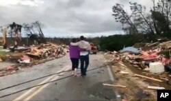 People walk amid debris in Lee County, Ala., after what appeared to be a tornado struck in the area Sunday, March 3, 2019.