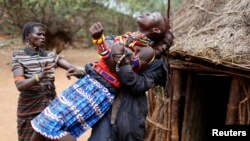 FILE - A man holds a girl as she tries to escape when she realized she is to to be married, about 80 km (50 miles) from the town of Marigat in Baringo County, Dec. 7, 2014.