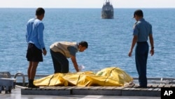 FILE - Crew members inspect bags containing bodies believed to be victims of AirAsia Flight 8501 on the deck of Indonesian Navy ship KRI Banda Aceh, on the Java Sea, Indonesia, Friday, Jan. 23, 2015.