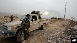 Pejuang Kurdi menembakkan senjatanya ke arah posisi militan Negara Islam (ISIS) (29/1). (AP/Bram Janssen)