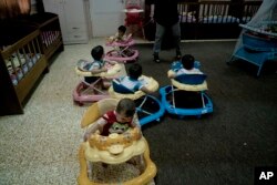 FILE - Babies toddle around in walkers at the state-run al-Zuhour Orphanage in Mosul, Iraq, Aug. 19, 2018. Orphanages are where wars play out: children abandoned in the chaos of battle, children born of rape and sexual slavery, babies left behind in the hospital in the hopes of a fresh start, and those left in state care after their parents are sentenced to death.