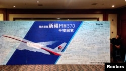 FILE - A policeman takes a nap beside a board written with messages for passengers onboard the missing Malaysia Airlines Flight MH370 during a closed meeting held between Malaysian representatives and Chinese relatives of passengers on Flight MH370 at Lido Hotel.