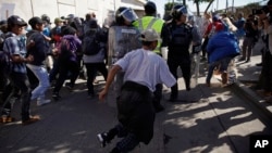 Migrants break past a line of police as they run toward the Chaparral border crossing in Tijuana, Mexico, Nov. 25, 2018, near the San Ysidro entry point into the U.S.