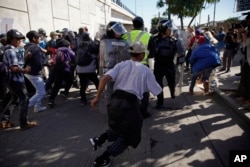 Migrants break past a line of police as they run toward the Chaparral border crossing in Tijuana, Mexico, Nov. 25, 2018, near the San Ysidro entry point into the U.S.