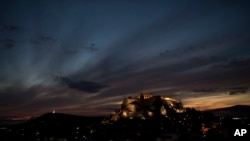 The sun sets behind the ancient Acropolis hill and the ruins of the fifth century B.C. Parthenon temple in Athens, on Thursday, Nov. 9, 2017.