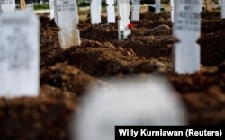 Bunga diletakkan di atas kuburan di areal pemakaman umat Islam yang disediakan pemerintah untuk korban Covid-19 di kompleks pemakaman Tegal Alur, Jakarta, 1 Desember 2020. (Foto: Reuters/Willy Kurniawan)