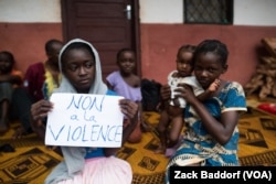 FILE - A young displaced Muslim girl holds a sign saying “No to Violence” at a displaced persons site, the Catholic church in Bangassou, Central African Republic.