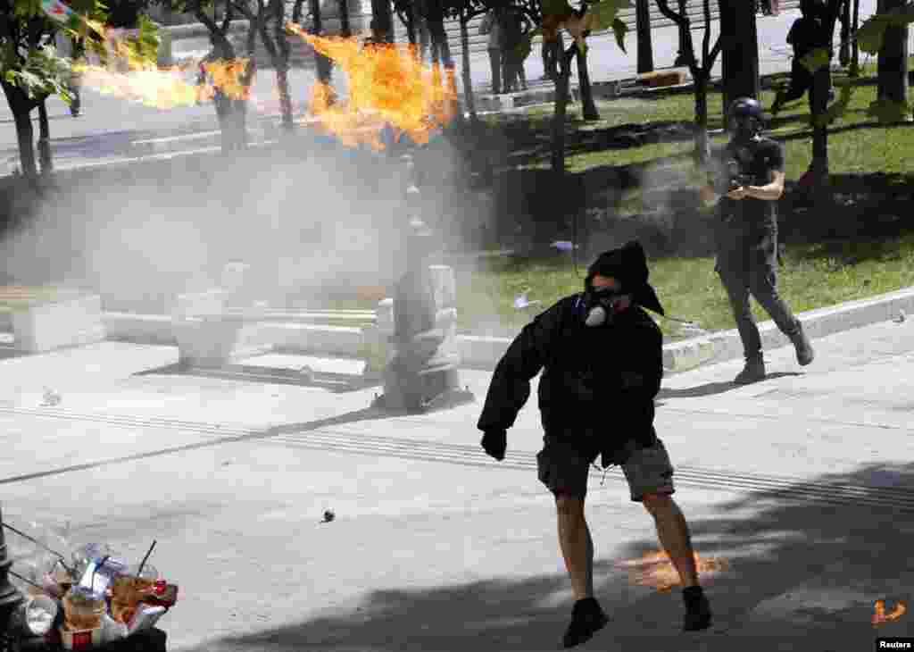 A demonstrator throws a molotov cocktail to riot police officers near Syntagma square during a 24-hour labor strike in Athens, Sept. 26, 2012.