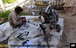FILE - In this file photo released on June 16, 2015, by Islamic State militant group supporters on an anonymous photo sharing website, Islamic State militants clean their weapons in Deir el-Zour city, Syria.