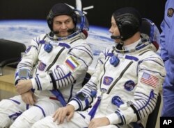 ນັກ​ບິນ​ອະ​ວະ​ກ​າດອາ​ເມ​ຣິ​ກັນ, ທ່ານ ນິກ ເຮກ (ຂວາ) ແລະ ທ່ານ ອາ​ເລັກ​ໄຊ ອົ​ຟ​ຈິນ​ນິນ ຈາກ​ອົງ​ການ​ອະ​ວະ​ກາດ ຣົ​ສ​ກົ​ສ​ມົ​ສ ລົມ​ກັນ ກ່ອນ​ຈະ​ຫລວດ​ຍິງ​ຍານ​ອະ​ວະ​ກາດ Soyuz MS-10 ຈະ​ທະ​ຍານ​ຂຶ້ນ​ໄປ​ສູ່​ທ້ອງ​ຟ້າ ເພື່ອ​ໄປ​ຫາ ຖານຍິງອະວະກາດສະໄໝໂຊຫວຽດ ໃນເມືອງ ໄບໂຄເນີ ຂອງ ກາຊັກສະຖານ ໃນ​ວັນ​ທີ 11 ຕຸ​ລາ, 2018