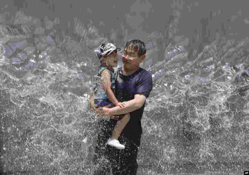 پدر و پسر ژاپنی از شدت گرما در این کشور به آب بازی پناه برده اند.