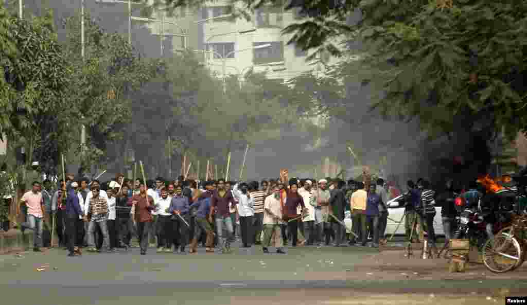 Jamaat-e-Islami party activists raise sticks as they approach police during a clash in Dhaka, Dec. 13, 2013. 
