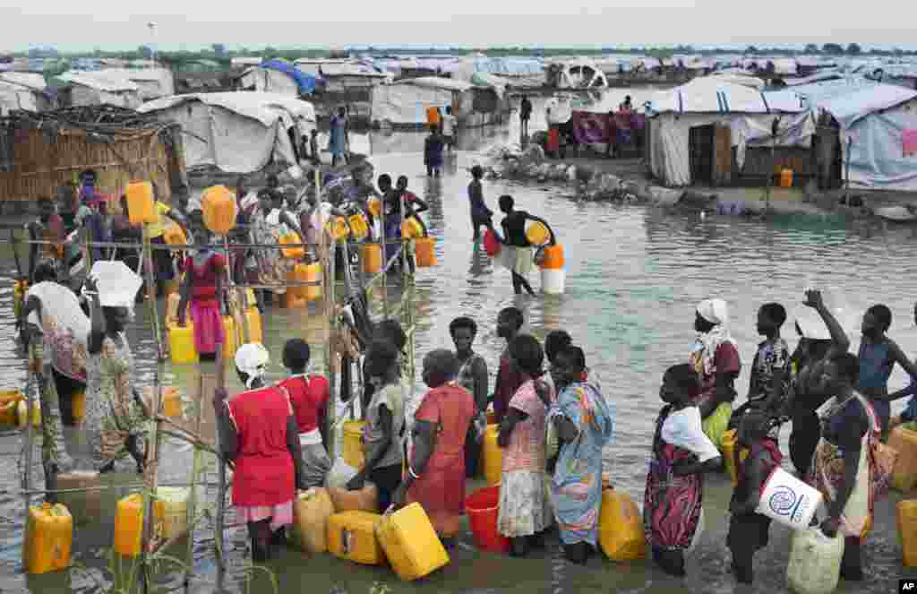 Des déplacées Sud Soudanaises font la queue dans une eau d&rsquo;inondation atteignant les genoux avant d&rsquo;accéder à l&rsquo;eau potable provenant d&#39;un forage, à un camp de fortune pour personnes déplacées situé dans la Mission des Nations Unies au Soudan du Sud (MINUSS) dans le village de Bentiu, au Soudan du Sud le lundi 22 septembre 2014. 