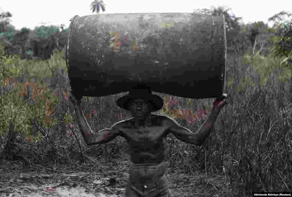 Nigéria: Ebiowei, 48 anos, carrega um barril de petróleo vazio para poder ser reabastecido numa refinaria ilegal