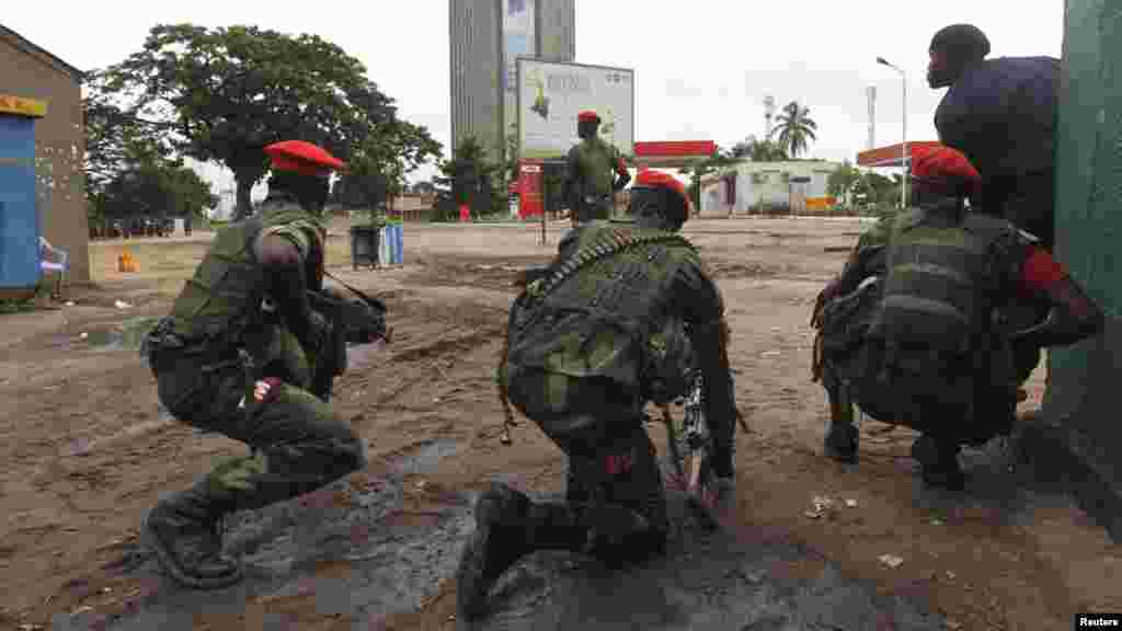 Congolese security officers position themselves as they secure the street near the state television headquarters (C) in the capital Kinshasa, DRC, Dec. 30, 2013.