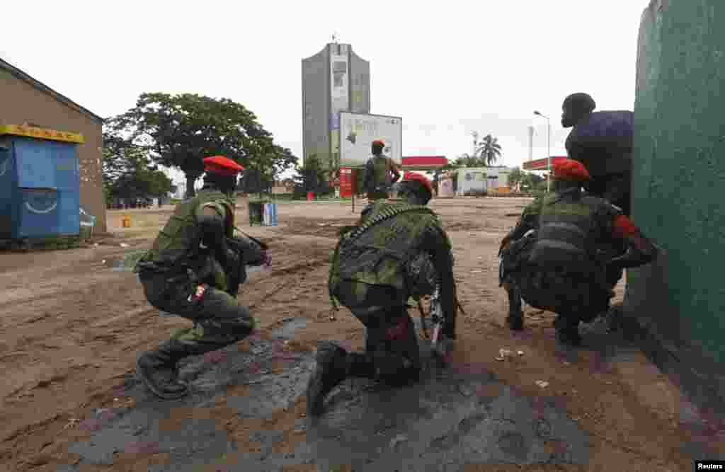 Congolese security officers position themselves as they secure the street near the state television headquarters (C) in the capital Kinshasa, DRC, Dec. 30, 2013.