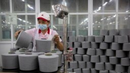 FILE - A worker packages spools of cotton yarn at a Huafu Fashion plant, as seen during a government-organized trip for foreign journalists, in Aksu in western China's Xinjiang Uyghur Autonomous Region, April 20, 2021.