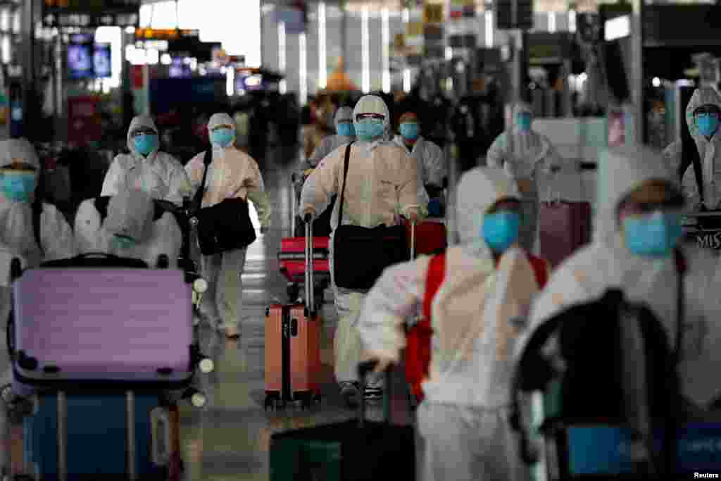 Chinese students living in Thailand wear protective suits walk at the Suvarnabhumi Airport before boarding a repatriation flight, in Bangkok.