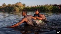 包括很多海地人在内的移民淌水越过格兰德河，返回美-墨边境墨西哥一侧的阿库尼亚城，以避免被美国遣返。(2021年9月20日)