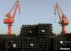 FILE - Cranes are seen above piles of steel pipes to be exported at a port in Lianyungang, Jiangsu province, China, Dec. 1, 2015.