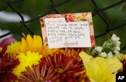 A card and flowers are displayed at a makeshift memorial near the site of a warehouse fire, Dec. 7, 2016, in Oakland.