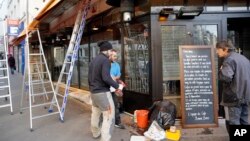 Beberapa orang pria tengah memperbaiki bagian depan cafe "La bonne biere", yang menjadi target serangan teroris di Paris, bulan November 2015 (3/12).