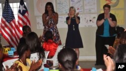 Michelle Obama (depan berdiri paling kiri) bersama para siswi sekolah di Kakata, Liberia, Senin (27/6).