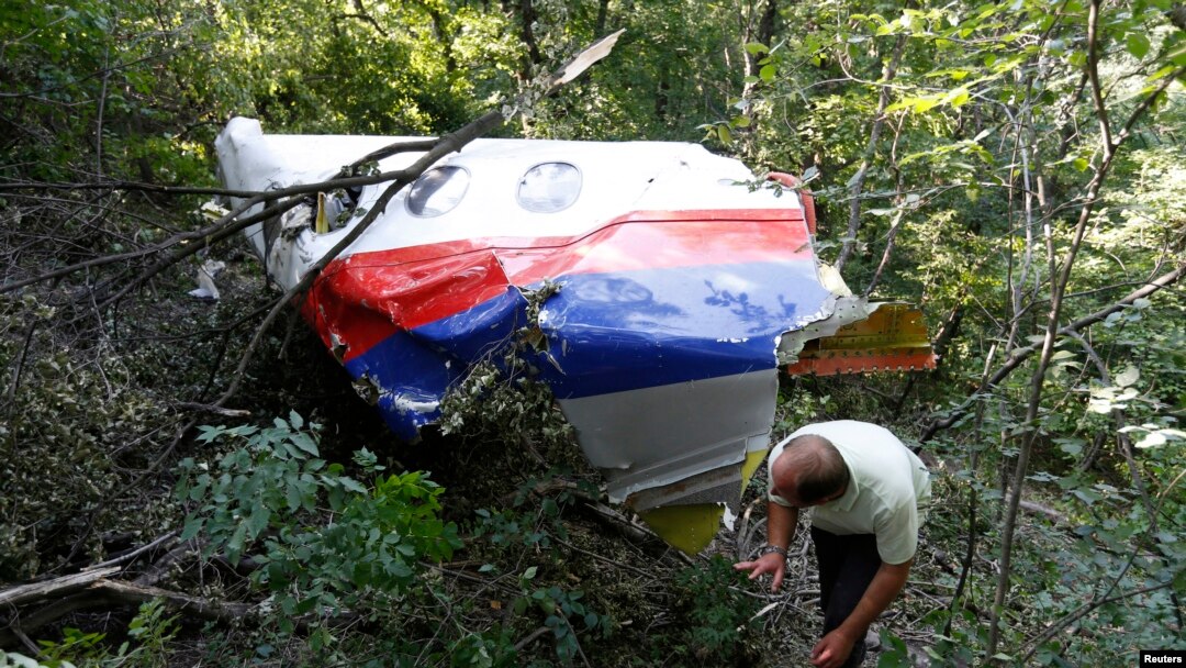 A man walks past wreckage at the crash site of Malaysia Airlines Flight MH17 near the village of Hrabove (Grabovo), Donetsk region, July 26, 2014.