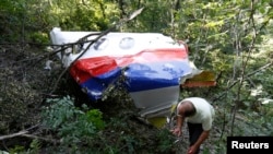 A man walks past wreckage at the crash site of Malaysia Airlines Flight MH17 near the village of Hrabove (Grabovo), Donetsk region, July 26, 2014.