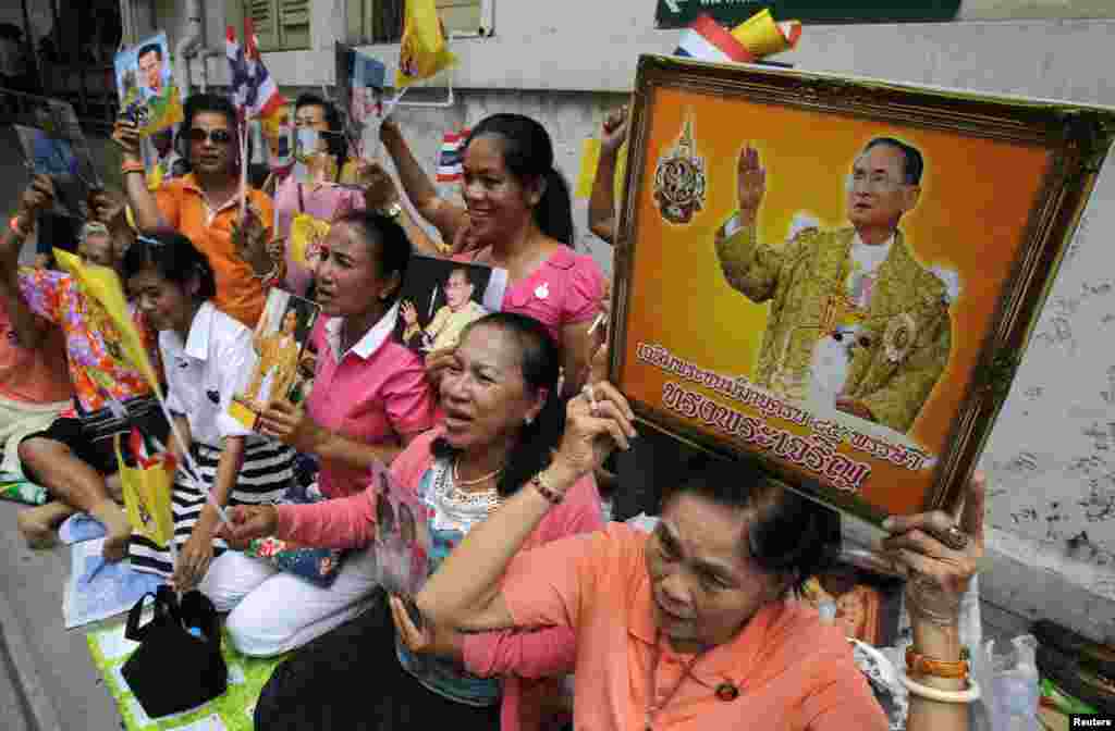 People hold portraits of Thailand's King Bhumibol Adulyadej as they wait for him to leave Siriraj hospital in Bangkok, August 1, 2013.