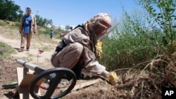 FILE - A de-miner searches for mines in Bagram, north of Kabul, Afghanistan, June 10, 2009.