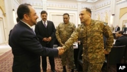 Afghan Foreign Minister Salahuddin Rabbani, left, shakes hands with a Pakistani officer during a meeting to discuss a road map for ending the war with the Taliban, at the Presidential Palace in Kabul, Afghanistan, Feb. 23, 2016.