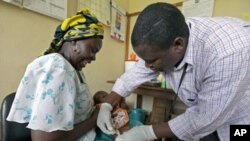 Iren Salama (L) holds her baby Pendo as it is given an injection as part of a malaria vaccine trial at a clinic in the Kenya coastal town of Kilifi, November 23, 2010 (file photo)