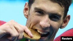 FILE - U.S. Olympic swimmer Michael Phelps poses with his gold medal. 