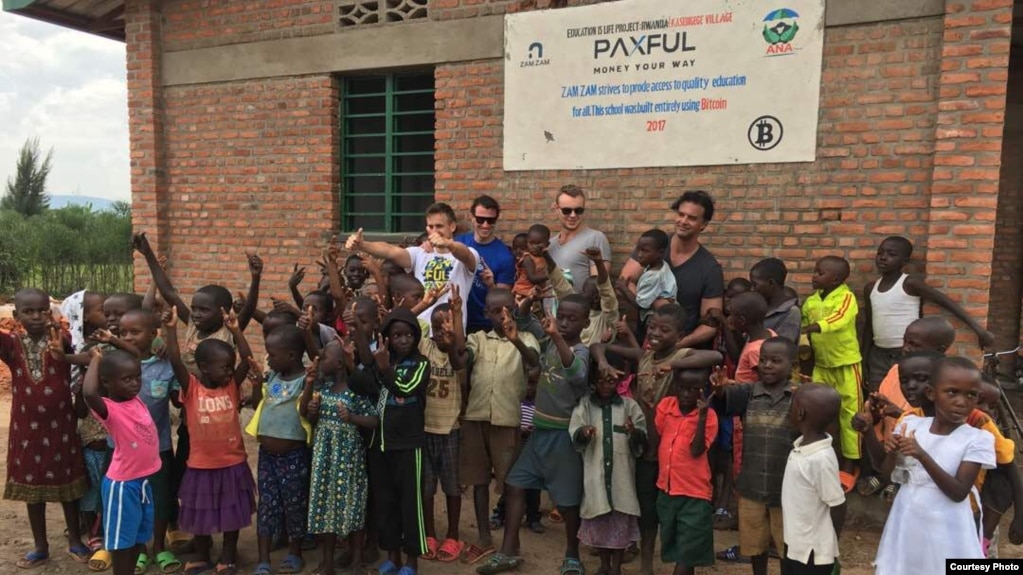 A new preschool, constructed with #BuiltWithBitcoin fundraising, brings new opportunities to youngsters in the Rwandan village of Kasebigege. Paxful CEO Ray Youssef, holding a child and not wearing sunglasses, led the fundraising effort. (Courtesy photo)