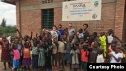 A new preschool, constructed with #BuiltWithBitcoin fundraising, brings new opportunities to youngsters in the Rwandan village of Kasebigege. Paxful CEO Ray Youssef, holding a child and not wearing sunglasses, led the fundraising effort. (Courtesy photo) 