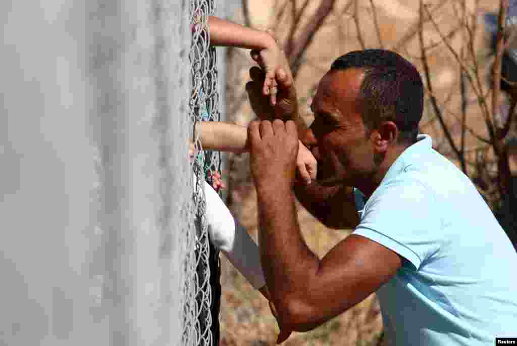 Ammar Hammasho from Syria who lives in Cyprus, kisses his children who arrived at the refugee camp in Kokkinotrimithia outside Nicosia, Cyprus.