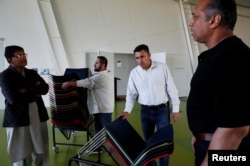 Sardar Faisal (2nd L) from Pakistan, a survivor of Christchurch shootings, helps to arrange chairs for a special prayers for the victims of the attacks in Christchurch, New Zealand, March 31, 2019.