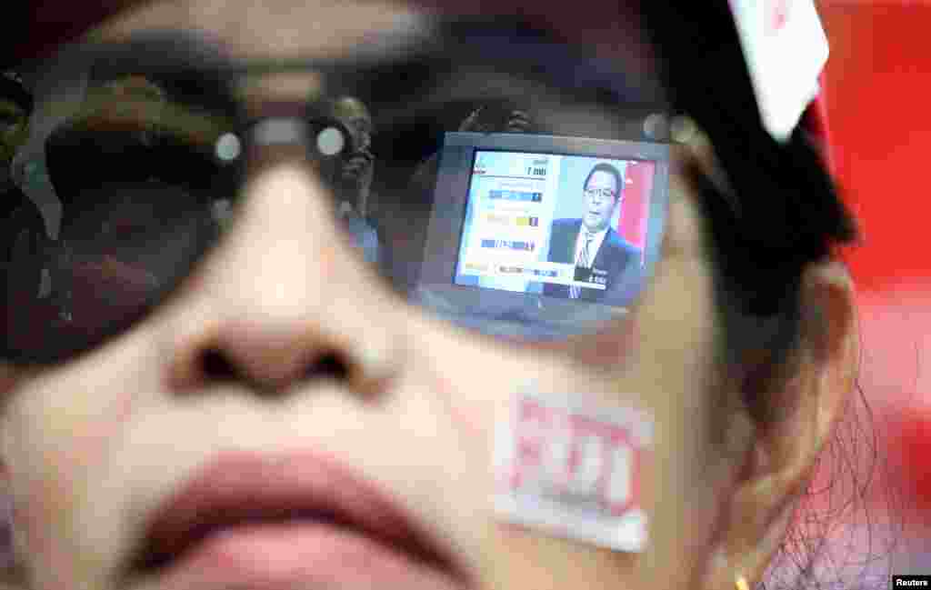 Live results are reflected in the glasses of a supporter of the Pheu Thai Party during the general election in Bangkok, Thailand, March 24, 2019.