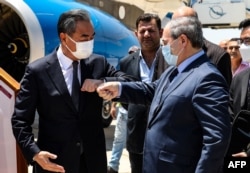 FILE - Syria's Foreign Minister Faisal Mekdad, right, receives his Chinese counterpart Wang Yi at the airport in the capital Damascus, July 17, 2021.