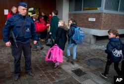 Children pass a police officer as they arrive for school in the center of Brussels, Nov. 25, 2015.