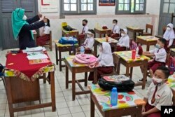 Para siswa mengenakan masker untuk membantu mencegah penyebaran COVID-19 pada hari pertama pembukaan kembali sekolah di sebuah sekolah dasar di Jakarta, Senin, 30 Agustus 2021. (Foto: AP)