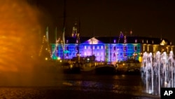 Blue Print by Dutch light designer Reier Pos is seen projected on the Nautical Museum, rear, as Arco, an art work by Austrian artist Teresa Mar is seen in the foreground, both installations are part of the Amsterdam Light Festival, Netherlands, Wednesday, Nov. 30, 2016. 