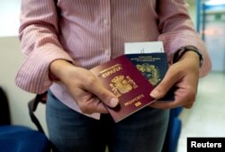 Mariana Elias, 27, shows her Venezuelan and Spanish passports at the Simon Bolivar International Airport, La Guaira, Venezuela, Jan. 14, 2019.