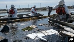 Cleanup contractors deploy skimmers and floating barriers known as booms to try to stop further oil crude incursion into the Wetlands Talbert Marsh in Huntington Beach, California, Oct. 3, 2021.