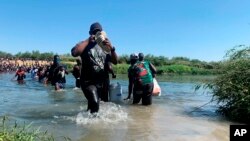 Migrants find an alternate place to cross between Mexico and the United States after access to a dam was closed, Sept. 19, 2021, in Ciudad Acuña, Mexico.