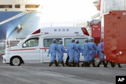 Members of Japan Self Defense Forces walk into the quarantined cruise ship Diamond Princess in the Yokohama Port Sunday, Feb. 9, 2020, in Yokohama, Japan.