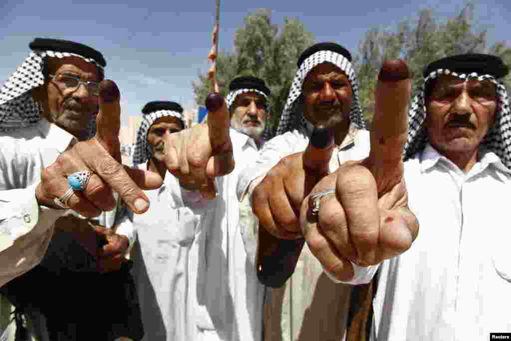 A group of men gesture with their ink-stained fingers after casting their ballots in the Iraqi parliamentary election, Najaf, ,April 30, 2014.