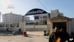 A Syrian rebel stands at the entrance to the headquarters of the Islamic State of Iraq and the Levant, after it fall to the Syrian rebels, in Aleppo, Syria, Wednesday Jan. 8, 2014 (AP Photo/Aleppo Media Center, AMC)